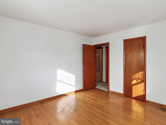 empty room with baseboards and light wood finished floors