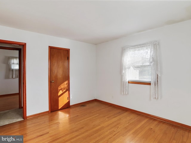 spare room featuring baseboards and light wood-style flooring