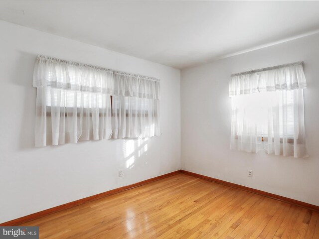 empty room with baseboards and light wood-style flooring