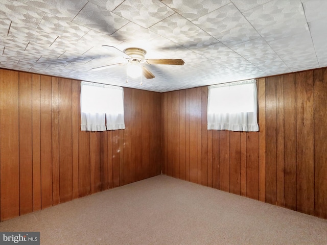 carpeted empty room featuring wood walls