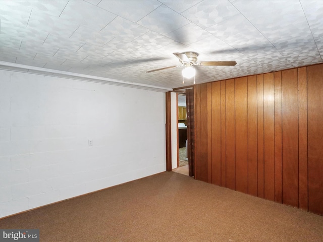 finished below grade area featuring wooden walls, a ceiling fan, and carpet flooring