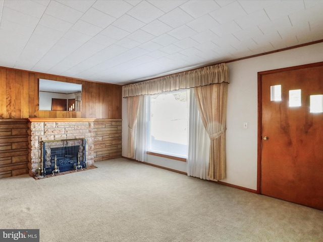 unfurnished living room featuring carpet floors, wood walls, and a fireplace