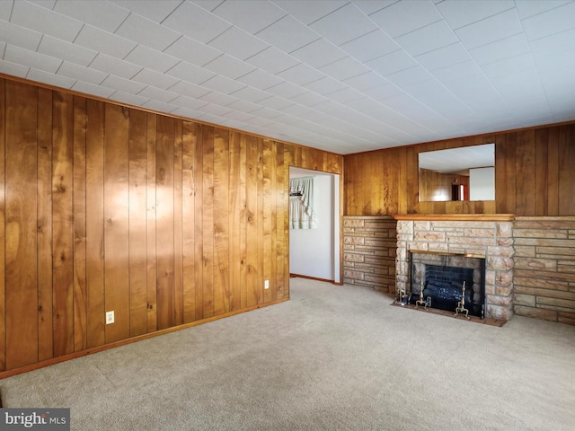 unfurnished living room featuring carpet flooring, wood walls, and a stone fireplace