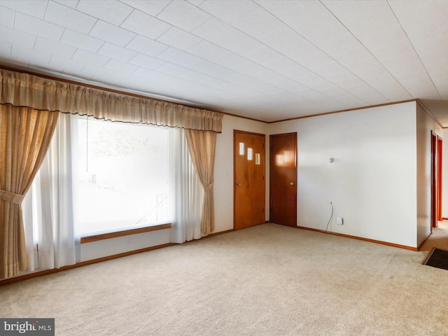 unfurnished living room with crown molding, carpet flooring, and baseboards