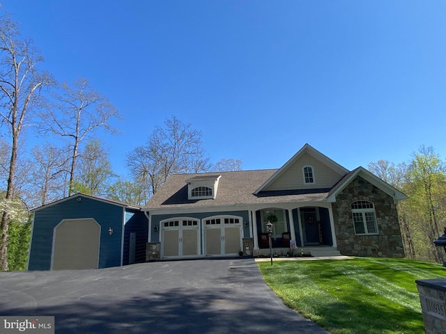 10935 Ravenwood Dr, Manassas, VA 20111 - view of front of home with covered porch, a garage, a front lawn, a shingled roof, and stone siding