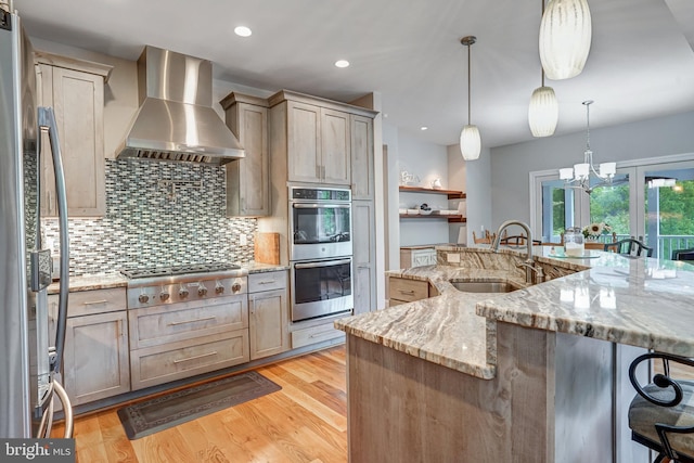 10935 Ravenwood Dr, Manassas, VA 20111 - kitchen featuring a breakfast bar area, wall chimney range hood, a sink, appliances with stainless steel finishes, and backsplash