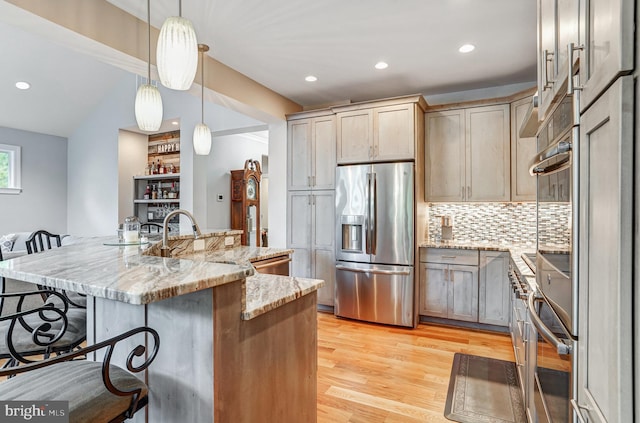 10935 Ravenwood Dr, Manassas, VA 20111 - kitchen featuring a breakfast bar, light stone counters, light wood finished floors, stainless steel appliances, and backsplash
