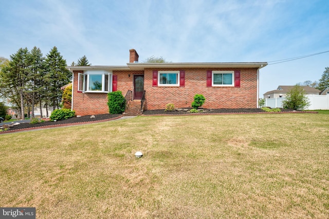 ranch-style house featuring brick siding, fence, a chimney, and a front lawn