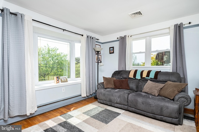 living area with visible vents, wood finished floors, and a healthy amount of sunlight
