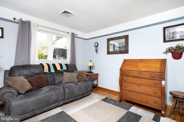 living area featuring baseboards, wood finished floors, and visible vents