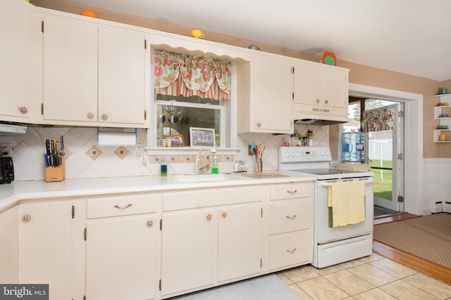 kitchen with backsplash, electric range, a sink, light countertops, and under cabinet range hood