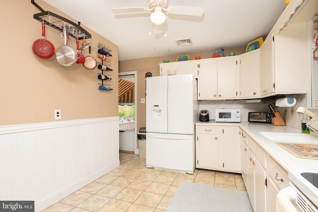 kitchen with white cabinets, light tile patterned flooring, ceiling fan, white appliances, and light countertops