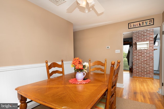 dining space with a ceiling fan, visible vents, wainscoting, and light wood-style flooring