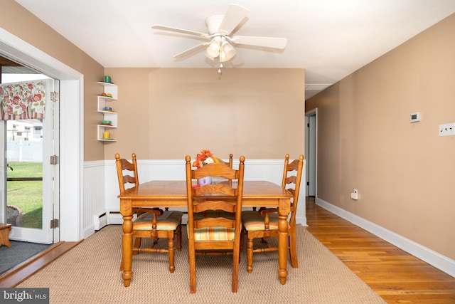 dining area with a baseboard radiator, light wood-style flooring, and ceiling fan
