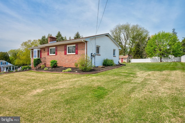 view of side of home with brick siding, a lawn, fence, and a chimney