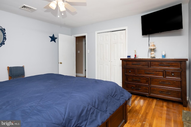 bedroom featuring ceiling fan, a closet, wood finished floors, and visible vents