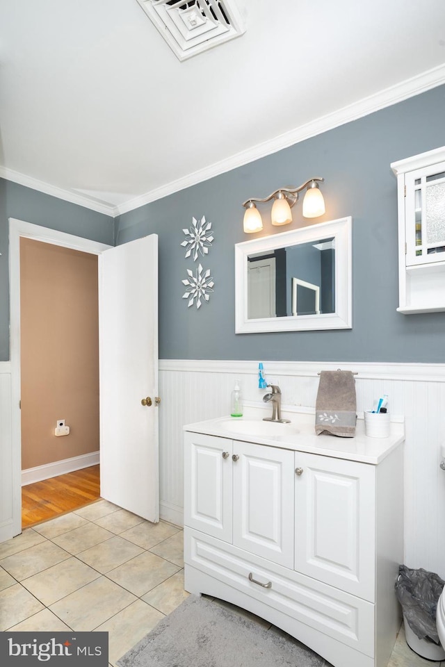 bathroom featuring crown molding, tile patterned flooring, a wainscoted wall, and vanity