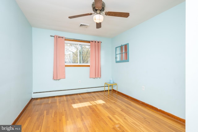 unfurnished room with baseboards, baseboard heating, hardwood / wood-style flooring, and visible vents