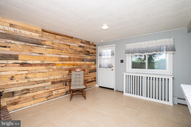 unfurnished room featuring wooden walls and a baseboard heating unit