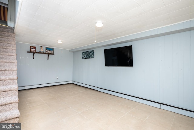 finished below grade area featuring baseboard heating and stairway