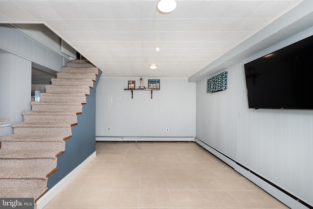 finished basement featuring tile patterned floors, baseboards, baseboard heating, and stairs