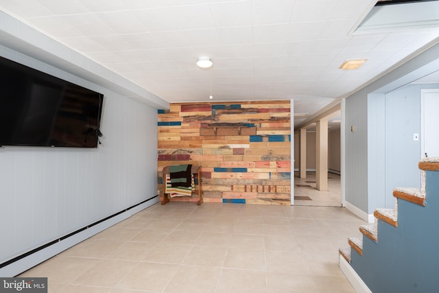finished basement with wood walls, a baseboard radiator, tile patterned floors, and stairs
