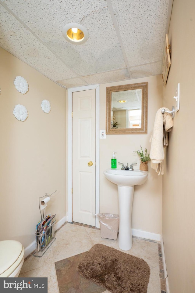 bathroom featuring baseboards, tile patterned flooring, and toilet