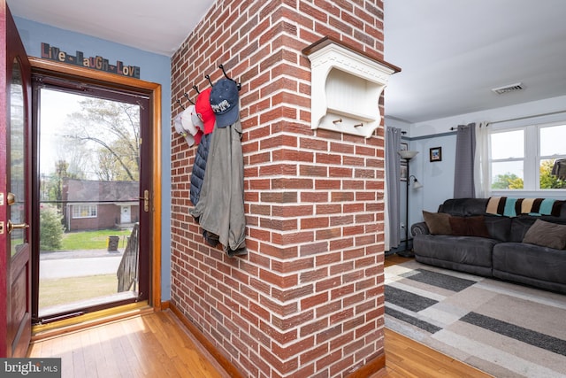 interior space featuring visible vents, brick wall, and hardwood / wood-style flooring