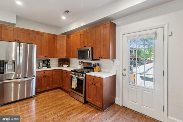 kitchen featuring light wood-style floors, light countertops, brown cabinetry, stainless steel appliances, and visible vents