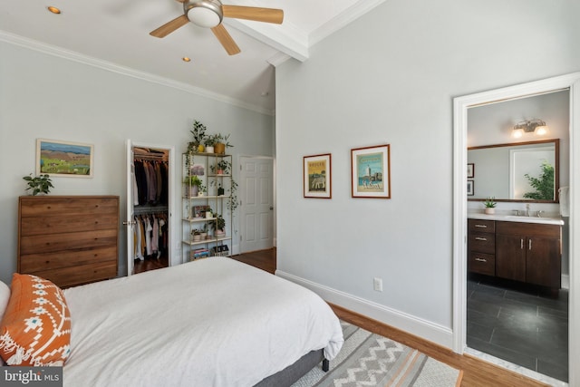 bedroom with a sink, baseboards, beamed ceiling, a spacious closet, and a closet