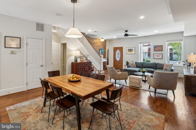 dining area with ceiling fan, baseboards, wood finished floors, visible vents, and stairway