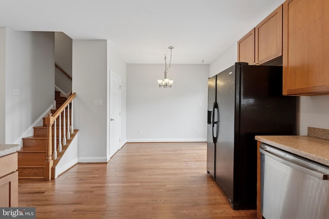 kitchen featuring dishwasher, an inviting chandelier, black fridge with ice dispenser, light countertops, and light wood-type flooring