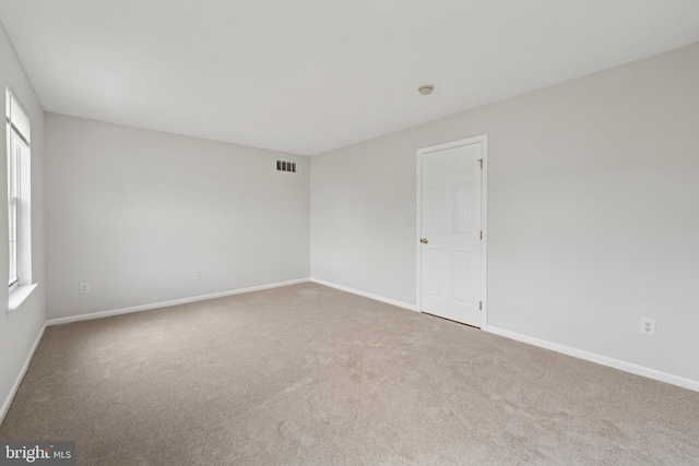 carpeted spare room featuring baseboards and visible vents