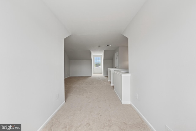 corridor featuring baseboards and light carpet