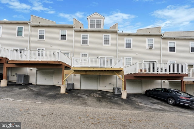 back of property featuring driveway, a garage, and central AC