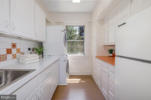 4000 Cathedral Ave NW Unit 435-436-437B, Washington, DC 20016 - kitchen featuring freestanding refrigerator, stacked washer / drying machine, white cabinetry, tasteful backsplash, and light countertops