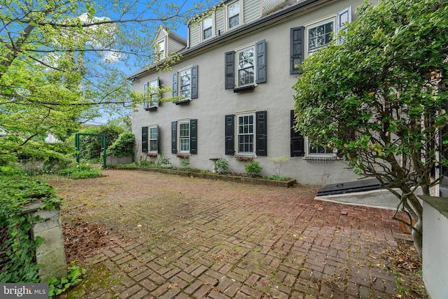 rear view of house featuring stucco siding and a patio