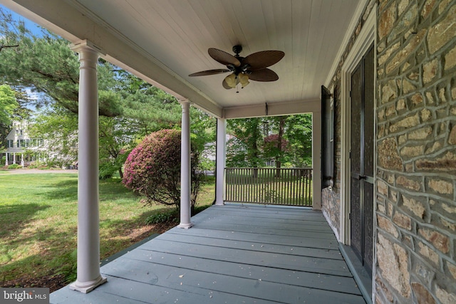 wooden terrace with ceiling fan and a yard