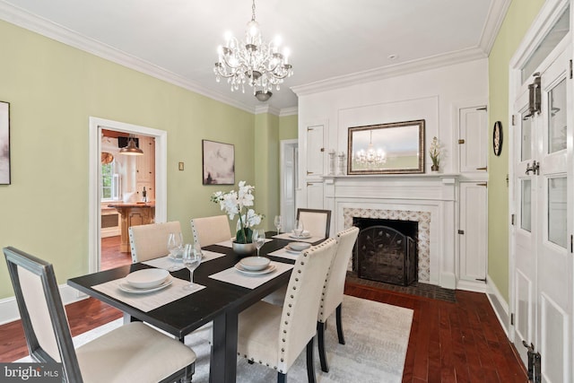 dining area with hardwood / wood-style floors, a chandelier, crown molding, a fireplace, and baseboards