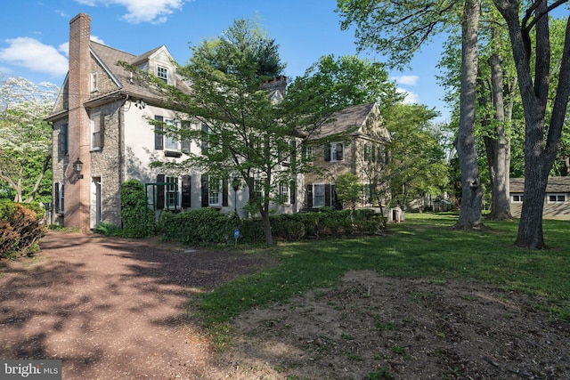 view of side of home with a chimney and a yard
