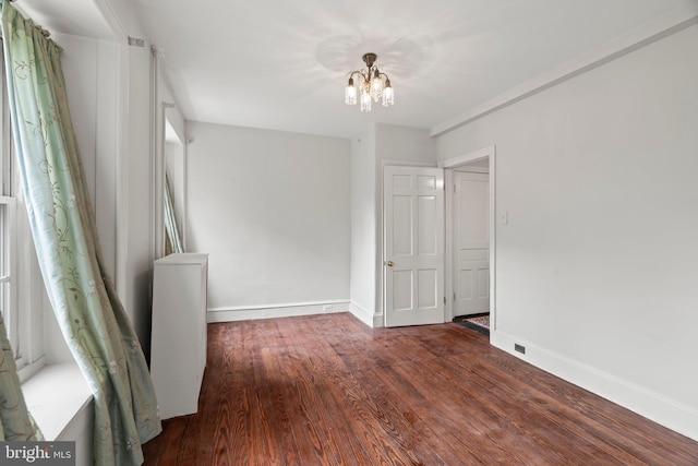 unfurnished bedroom with a chandelier, wood finished floors, and baseboards