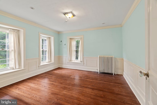 unfurnished room with radiator, wainscoting, wood finished floors, and crown molding