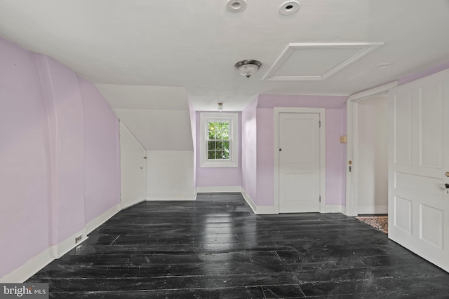 bonus room with baseboards, attic access, and dark wood-style floors