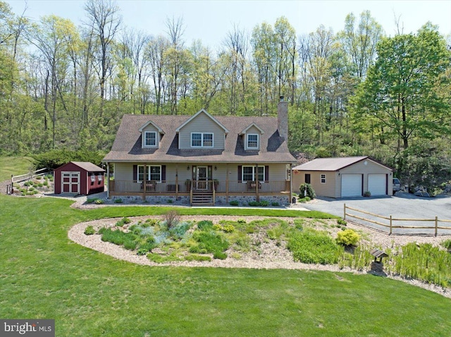 cape cod house with covered porch, a chimney, a front yard, a detached garage, and an outdoor structure