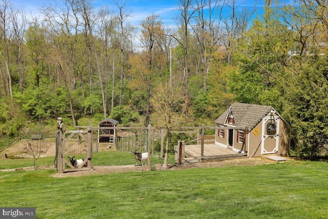 view of yard featuring a storage unit, an outdoor structure, a deck, and a wooded view