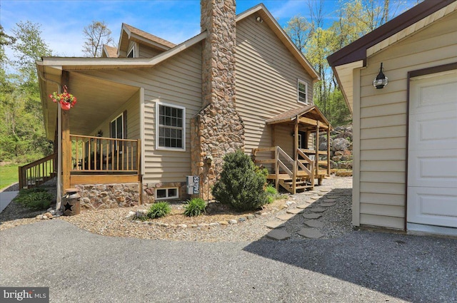view of property exterior with a porch, stairway, and a chimney