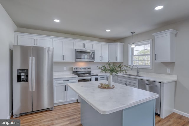 kitchen with white cabinets, appliances with stainless steel finishes, a sink, and light countertops