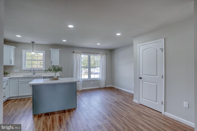 kitchen featuring a sink, light countertops, light wood-style floors, and white cabinetry