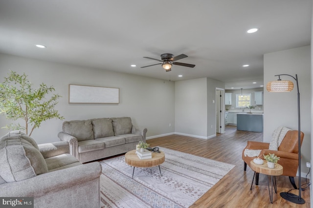 living room featuring recessed lighting, ceiling fan, baseboards, and light wood-type flooring