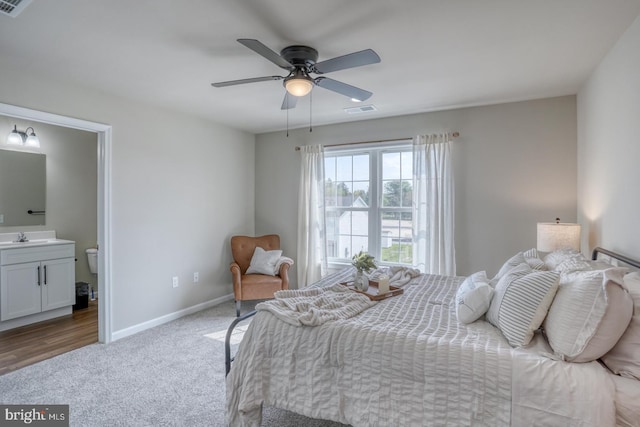 carpeted bedroom with visible vents, a sink, baseboards, and ensuite bathroom